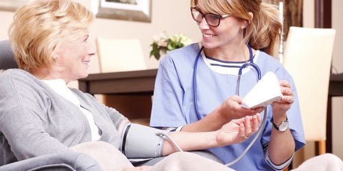 middle aged at home care giver helping senior woman